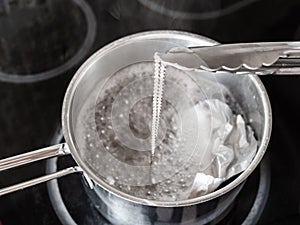 Tongs removes clean chain from boiling solution