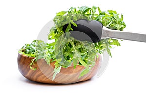 Tongs with rocket salad leaves isolated on white