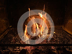 Tongues of fire pass through the grill net at night