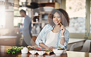 Tonights supper will be something healthy. Portrait of a young woman holding a carrot while preparing a healthy meal