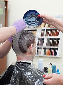 Toning gray hair on the man`s head in beauty salon