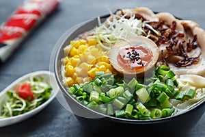 Tonkotsu ramen, japanese noodle soup with pork belly, corn, spring onion and nitamago on top photo