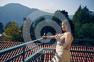 Tonned portrait of a beautiful woman drinking healthy juice in the terrace or balcony, against the Italian Alps backdrop