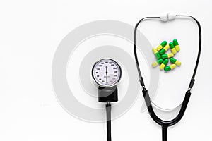 Tonometer, blood pressure monitor, and pills on a white background. Concept of heart treatment and pressure control. Space for