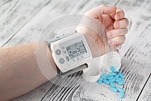 Tonometer high blood pressure indication on the male& x27;s arm. hypertension medical pills on the background