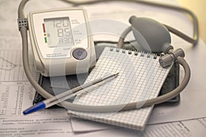 Tonometer and notebook with a fountain pen on the background of medical graphs and diagnoses, place for text