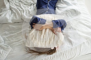 Too lazy to get out of bed, a woman covers her face with a pillow photo