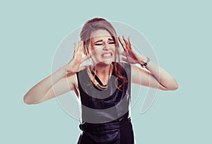 Too loud. Closeup portrait stressed woman covers ears with hands yelling screaming with temper tantrum isolated light green wall