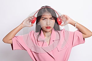 Too loud.  portrait of  young asian woman  holding  headphones and making unhappy face