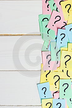 Too Many Questions on wooden background. Pile of colorful paper notes with question marks. top view copy space