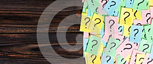 Too Many Questions on wooden background. Pile of colorful paper notes with question marks. top view copy space