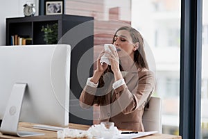 Too many sneezes are interrupting her way towards success. Shot of a young businesswoman suffering with allergies at