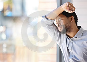 Too much to do, too much to stress out. Shot of a young businessman looking stressed out while standing at a window in