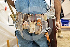 Tool belt on masonry construction worker wearing coveralls