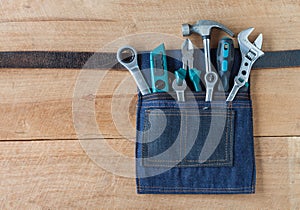 Tool belt with tools on wooden board background