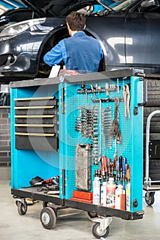 Tool Cart With Male Mechanic Repairing Car