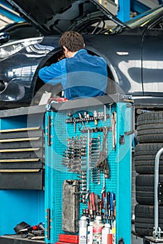 Tool Cart With Male Mechanic Repairing Car