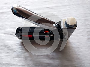 The tool for construction works, a stsepler of black color connects objects to the white handle metal brackets,