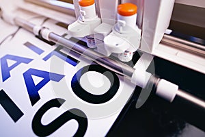 tool head of cutting plotter equiped with two adjustable blades makes adhesive lettering from black vinyl foil in bright light