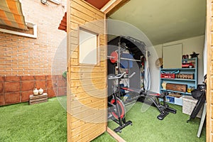 A tool shed transformed into a home gym with artificial grass flooring