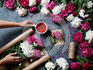 Tools and accessories florists need for making up a bouquet out of peonies: kraft paper, scissors, string, karkade tea