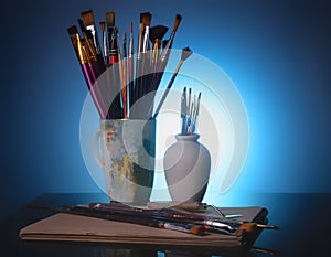 Tools of the artist - brushes and palette knife on a  blue background