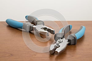 Tools, blue pliers on a walnut table