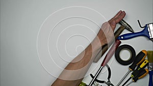 Tools for building repair on a white background. A man's hand rakes everything freeing the background for the inscription