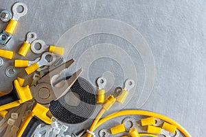 Tools, components and accessories used in electrical installations, on metal gray background with copy space