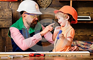 Tools construction. Father teaching little son to use carpenter tools and hammering. Father helping son at workshop.