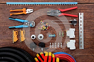 Tools for electrical work laid out on a wooden surface of brown. Top view