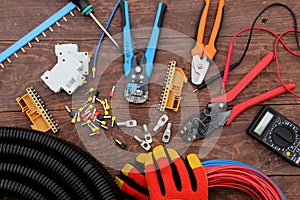 Tools for electrical work laid out on a wooden surface of brown. Top view