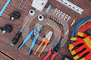 Tools for electrical work laid out on a wooden surface of brown. Top view