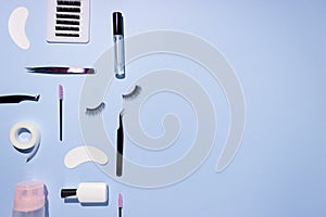 Tools for eyelash extension on a blue background. Artificial eyelashes, self-care. Tweezers, glue, and other tools for lashmaker