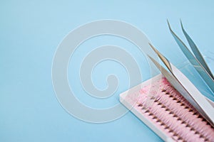 tools for Eyelash Extension Procedure. Two tweezers and box with false lashes on blue background. copyspace mockup - Beauty and fa