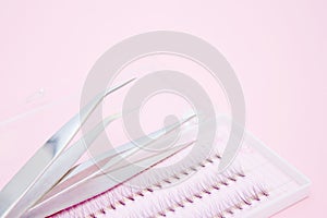Tools for Eyelash Extension Procedure. Two tweezers and box with false lashes on pink background. copyspace mockup - Beauty and