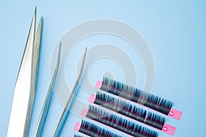 tools for Eyelash Extension Procedure. Two tweezers with false lashes on blue background. copyspace mockup - Beauty and fashion co