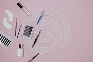Tools for eyelash extensions on a pink background, free space for text, top view. Artificial eyelashes, tweezers, microbrushes,