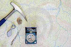 The tools of the geologist laid out on a topographic map. Background