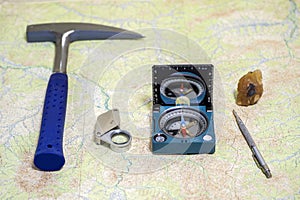 The tools of the geologist laid out on a topographic map. Background