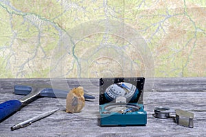 Tools geologist laid out on a wooden table on the background of a topographic map. Background