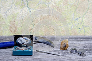 Tools geologist laid out on a wooden table on the background of a topographic map. Background