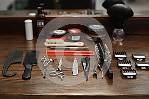 Tools for a hairdresser on a dark wooden table at a barber shop - scissors, nozzles, combs and razors