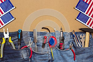 Tools in jeans on masonite plate with US flags, top view, patriotic holiday concept of labor day, flatlay with copyspace photo