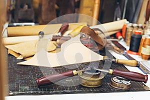 Tools and leather at cobbler workplace. Set of leather craft tools on background