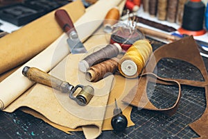 Tools and leather at cobbler workplace. Set of leather craft tools on wooden background