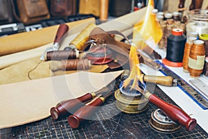 Tools and leather at cobbler workplace. Set of leather craft tools on wooden background