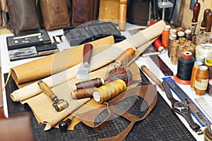 Tools and leather at cobbler workplace. Set of leather craft tools on wooden background