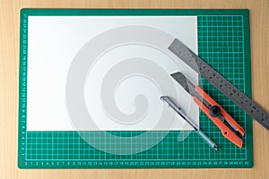 tools for making crafts. Kater, ruler, pen, and white paper on a cutting matt photo