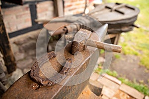 Tools in an old blacksmith& x27;s workshop. Horseshoe and hammer on a large anvil